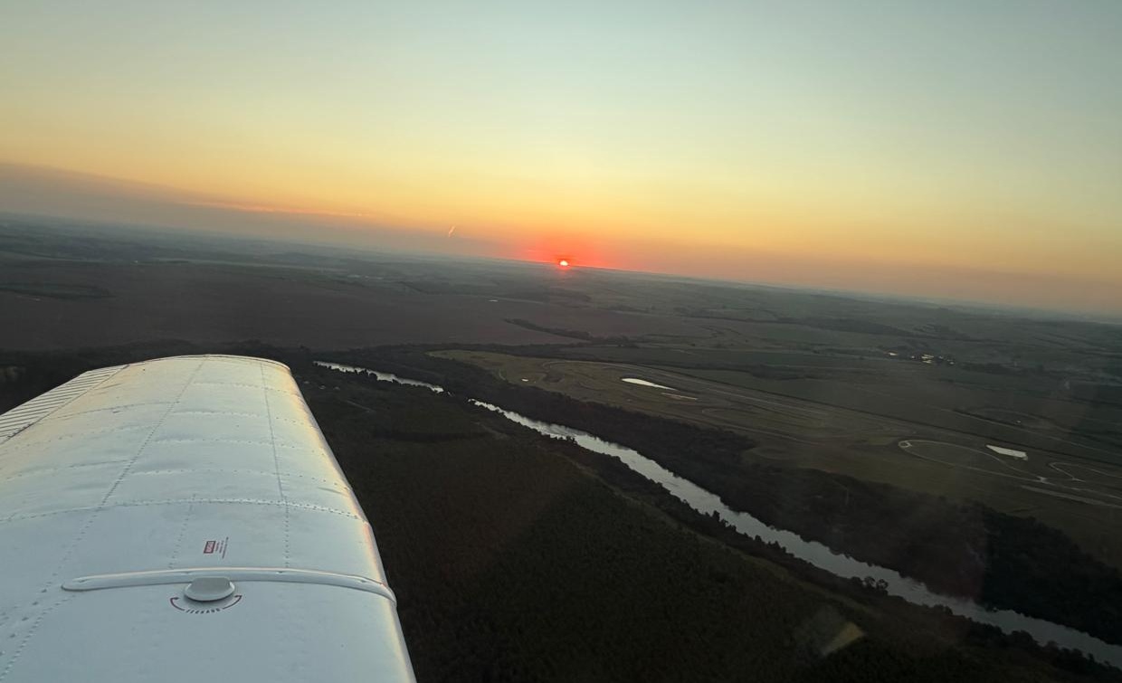 Vista aérea com a asa do Tupi, rio e pôr do sol